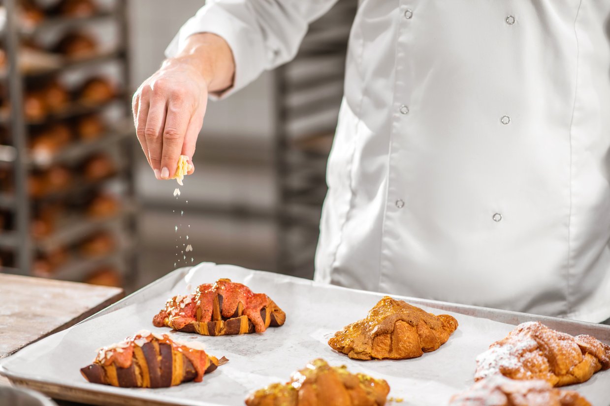 Pastry Chef Sprinkling Almond on Croissant  