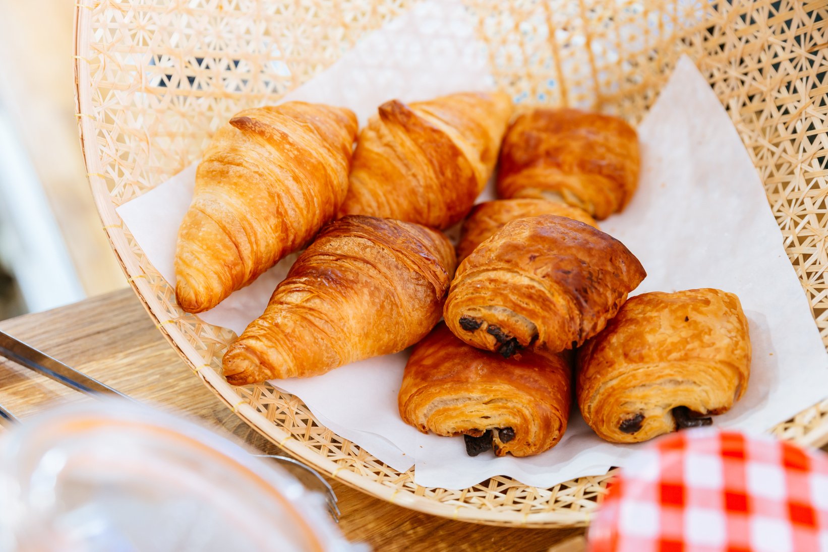 Fresh baked Classic Butter Croissants and Raisin Croissant inside weaving basket.